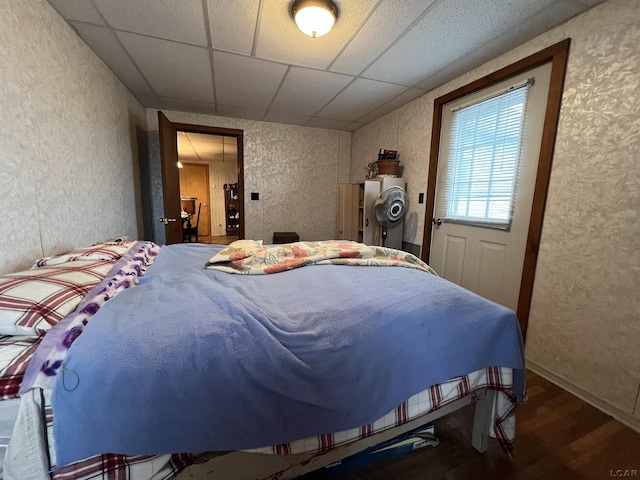 bedroom with a drop ceiling and wood finished floors