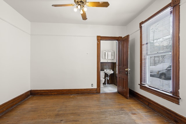 unfurnished room featuring a sink, a ceiling fan, baseboards, and wood finished floors