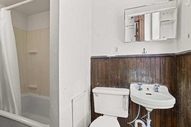 full bath with toilet, shower / tub combo, wainscoting, a sink, and wooden walls