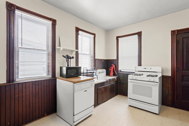 kitchen with white appliances, a wainscoted wall, wood walls, white cabinetry, and open shelves