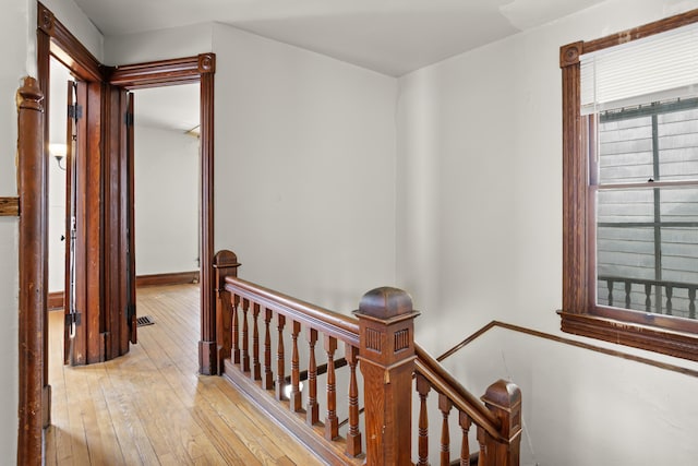 corridor with an upstairs landing and light wood-style floors