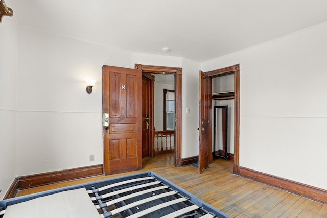 unfurnished bedroom with a closet, baseboards, and hardwood / wood-style flooring