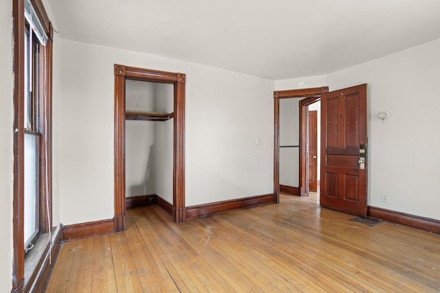 unfurnished bedroom featuring light wood-style floors, a closet, visible vents, and baseboards