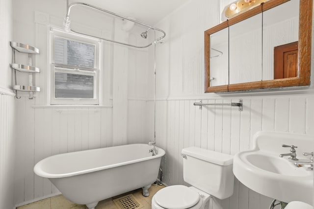 bathroom with toilet, a sink, and a freestanding bath