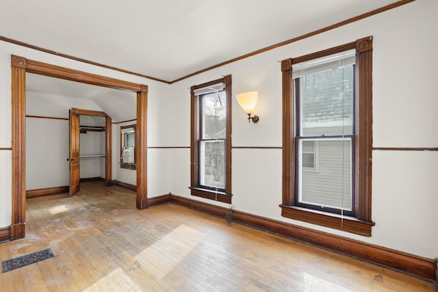 spare room with light wood finished floors, ornamental molding, visible vents, and baseboards