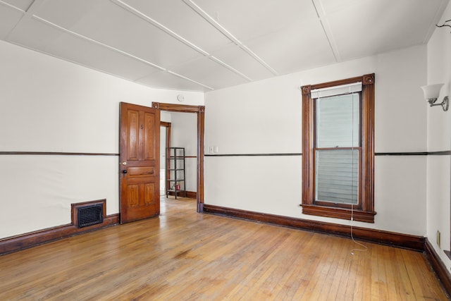 unfurnished room with light wood-style flooring, visible vents, and baseboards