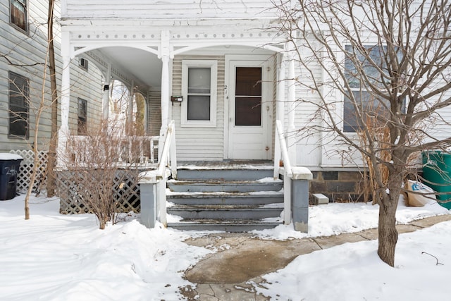 snow covered property entrance featuring covered porch