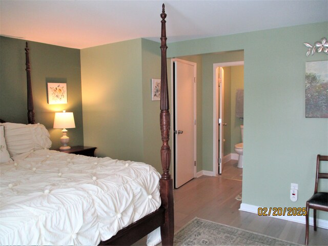 bedroom with baseboards, wood finished floors, and connected bathroom