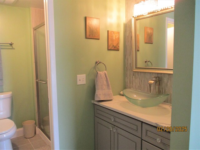 bathroom featuring toilet, vanity, a shower stall, baseboards, and tile patterned floors