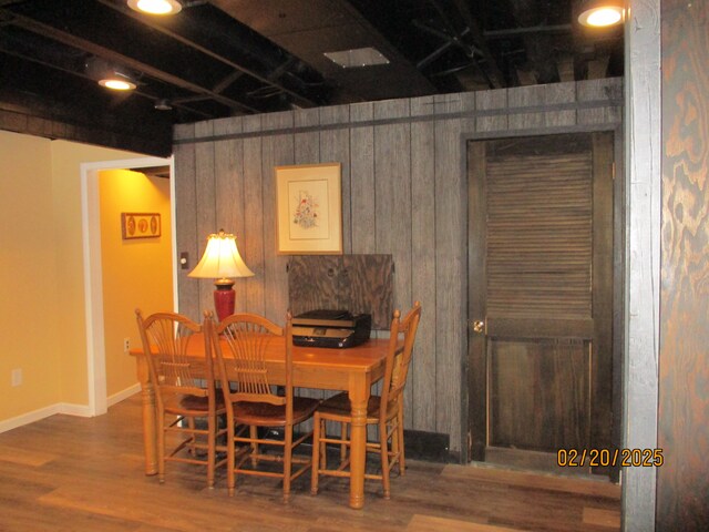 dining area featuring wooden walls, baseboards, and wood finished floors