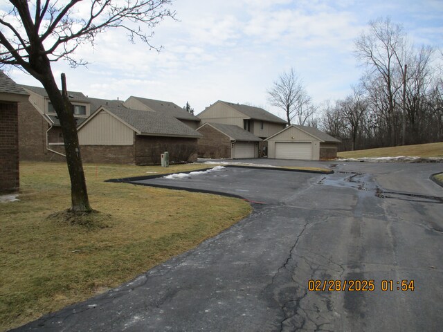 view of front of property with brick siding, a detached garage, and a front yard