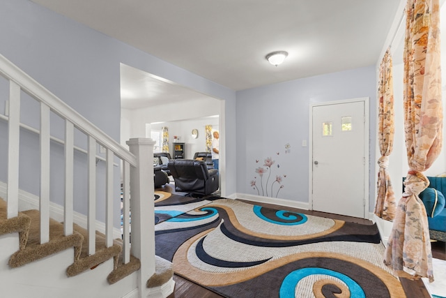 entryway featuring stairway, wood finished floors, and baseboards