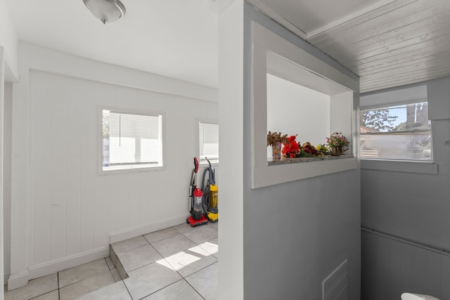 hallway featuring visible vents, plenty of natural light, baseboards, and light tile patterned floors