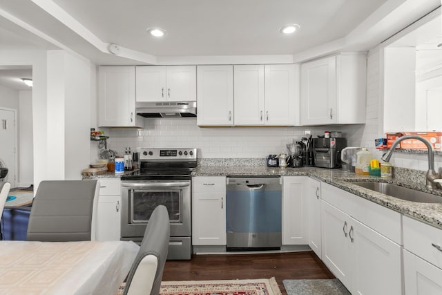 kitchen with dark wood-style floors, stainless steel appliances, under cabinet range hood, white cabinetry, and a sink