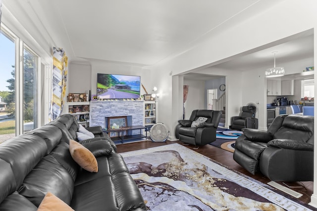 living area with stairway, wood finished floors, and a stone fireplace