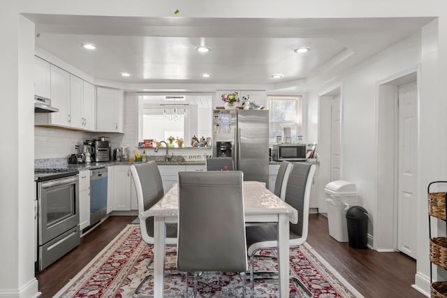 kitchen featuring stainless steel appliances, dark wood-style flooring, white cabinetry, and under cabinet range hood