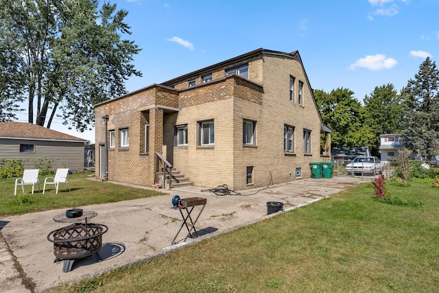 back of house featuring brick siding, a patio, a lawn, an outdoor fire pit, and entry steps