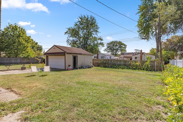 view of yard with a garage, a fenced backyard, an outdoor structure, and driveway