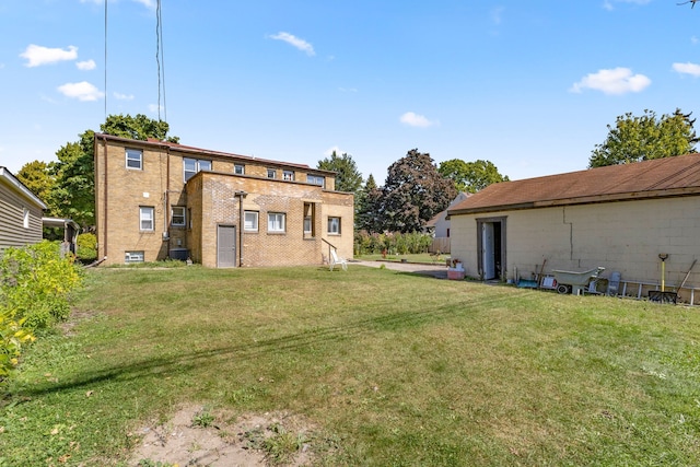 back of property with brick siding, central AC, and a yard