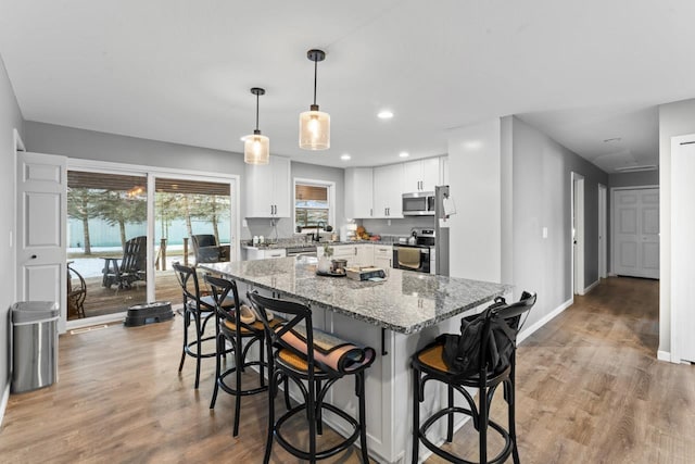 5235 Lahring Rd, Linden, MI 48451 - kitchen with a kitchen bar, a center island, light stone countertops, light wood finished floors, and stainless steel appliances
