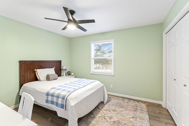 bedroom featuring ceiling fan, a closet, wood finished floors, and baseboards