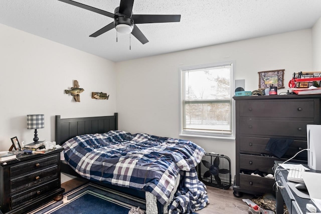 bedroom featuring ceiling fan, a textured ceiling, and wood finished floors