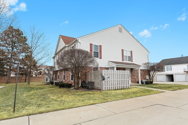 view of front of home with brick siding, concrete driveway, fence, a garage, and a front lawn