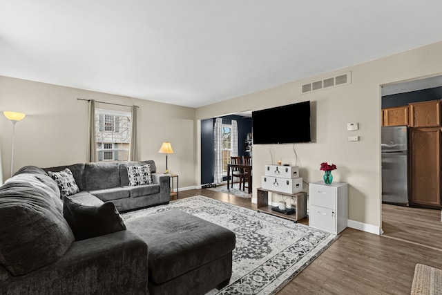 living room with wood finished floors, visible vents, and baseboards