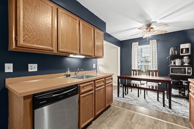 kitchen featuring stainless steel appliances, light countertops, a ceiling fan, a sink, and light wood-type flooring