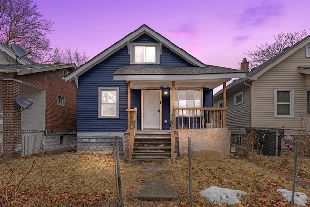 bungalow-style home featuring covered porch, a shingled roof, and fence