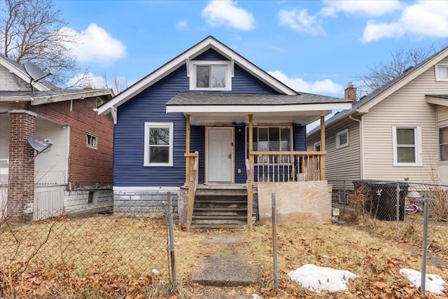 bungalow-style house with a porch, a shingled roof, and fence