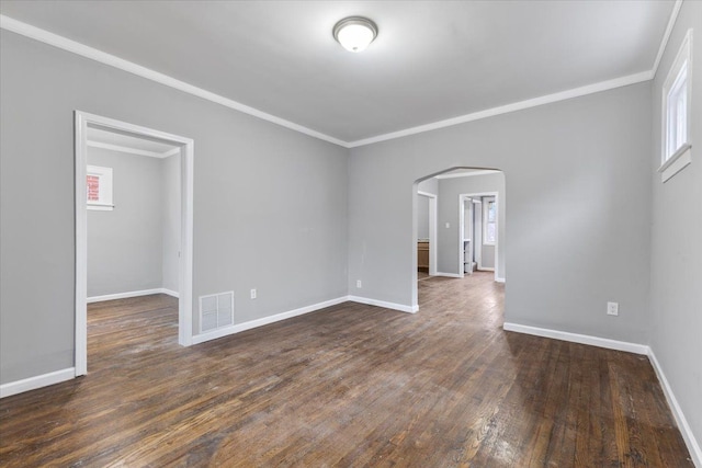 spare room with baseboards, visible vents, arched walkways, ornamental molding, and dark wood-style flooring