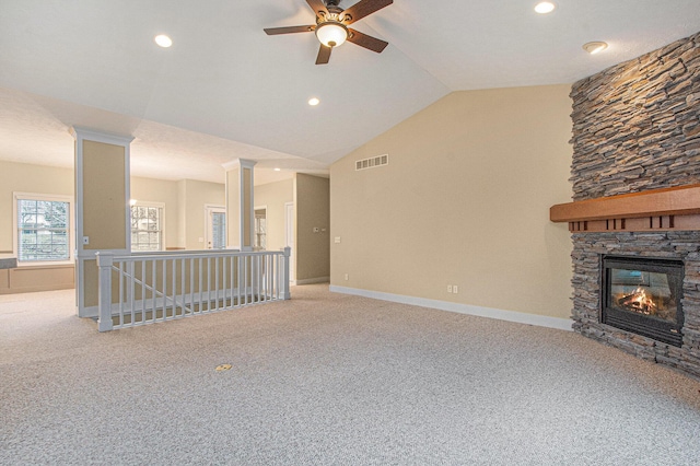 unfurnished living room with lofted ceiling, visible vents, carpet flooring, a stone fireplace, and baseboards