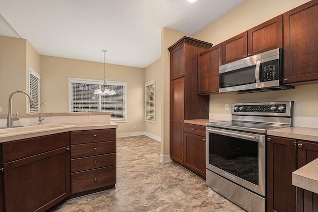 kitchen featuring appliances with stainless steel finishes, light countertops, a sink, and an inviting chandelier