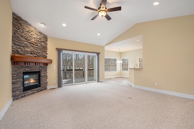 unfurnished living room with carpet, vaulted ceiling, a stone fireplace, and baseboards