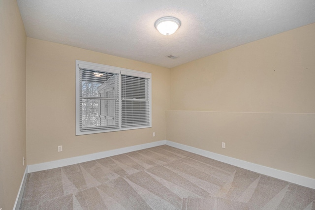 carpeted spare room featuring visible vents, a textured ceiling, and baseboards