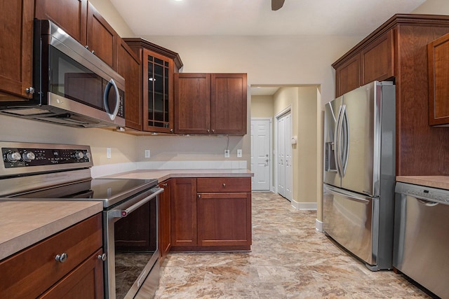 kitchen featuring light countertops, appliances with stainless steel finishes, glass insert cabinets, ceiling fan, and baseboards