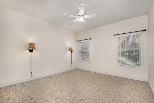 spare room with a healthy amount of sunlight, baseboards, a ceiling fan, and light colored carpet