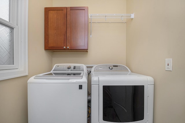 clothes washing area with washing machine and dryer and cabinet space