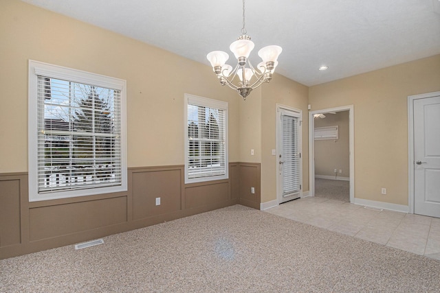 spare room with wainscoting, carpet flooring, visible vents, and a healthy amount of sunlight