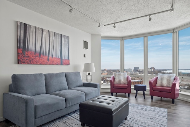 living room with visible vents, wood finished floors, a wealth of natural light, and floor to ceiling windows