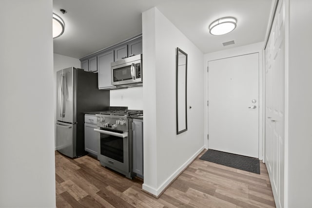 kitchen featuring gray cabinetry, stainless steel appliances, wood finished floors, visible vents, and dark countertops