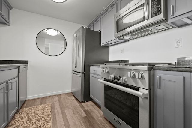 kitchen with stainless steel appliances, light wood finished floors, and gray cabinetry