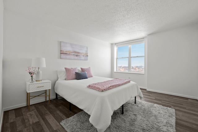 bedroom featuring a textured ceiling, baseboards, and wood finished floors