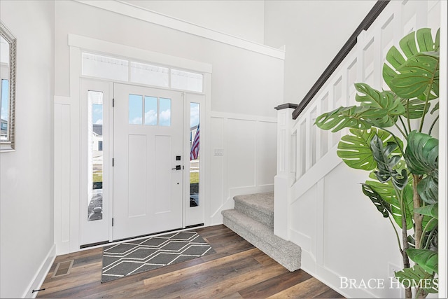 entrance foyer with stairs, dark wood-style flooring, and a decorative wall