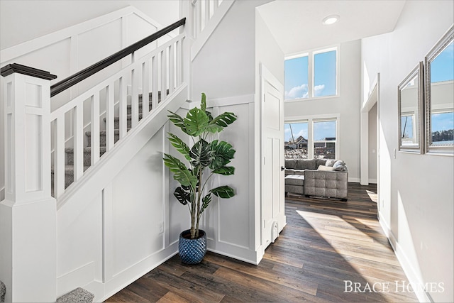 stairway featuring recessed lighting, baseboards, a high ceiling, and wood finished floors