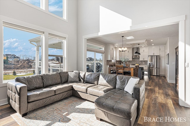 living room with a towering ceiling, baseboards, dark wood finished floors, and a notable chandelier