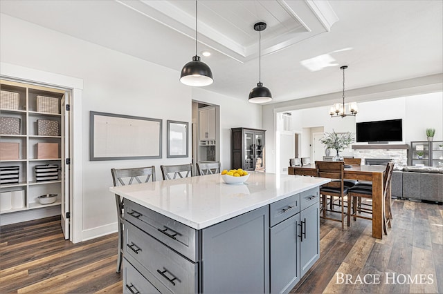 kitchen with dark wood-style floors, a kitchen island, open floor plan, hanging light fixtures, and gray cabinetry