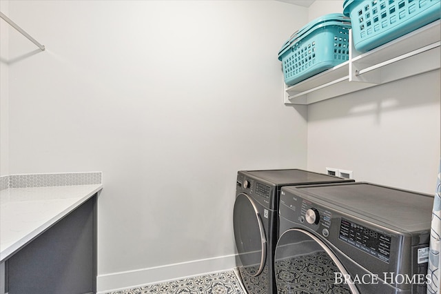 clothes washing area with washer and dryer, laundry area, and baseboards