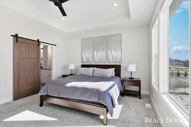 bedroom with a barn door, baseboards, a raised ceiling, and light colored carpet